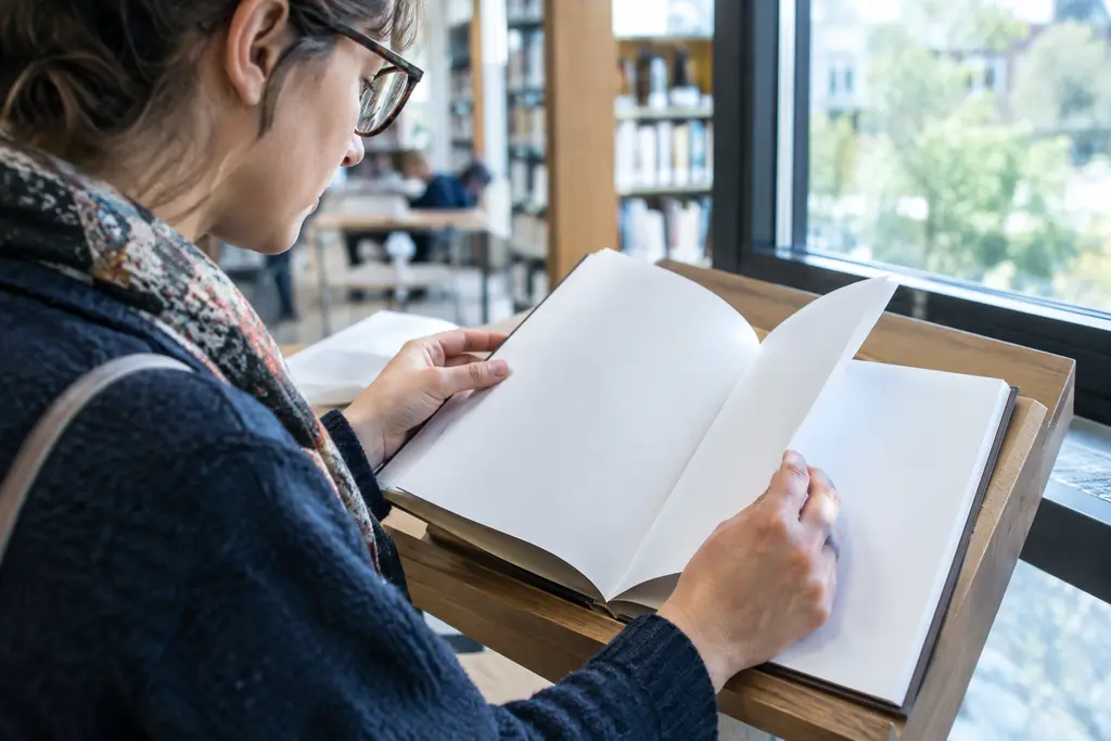Une lectrice consulte un document aux pages vierges dans une bibliothèque lumineuse.