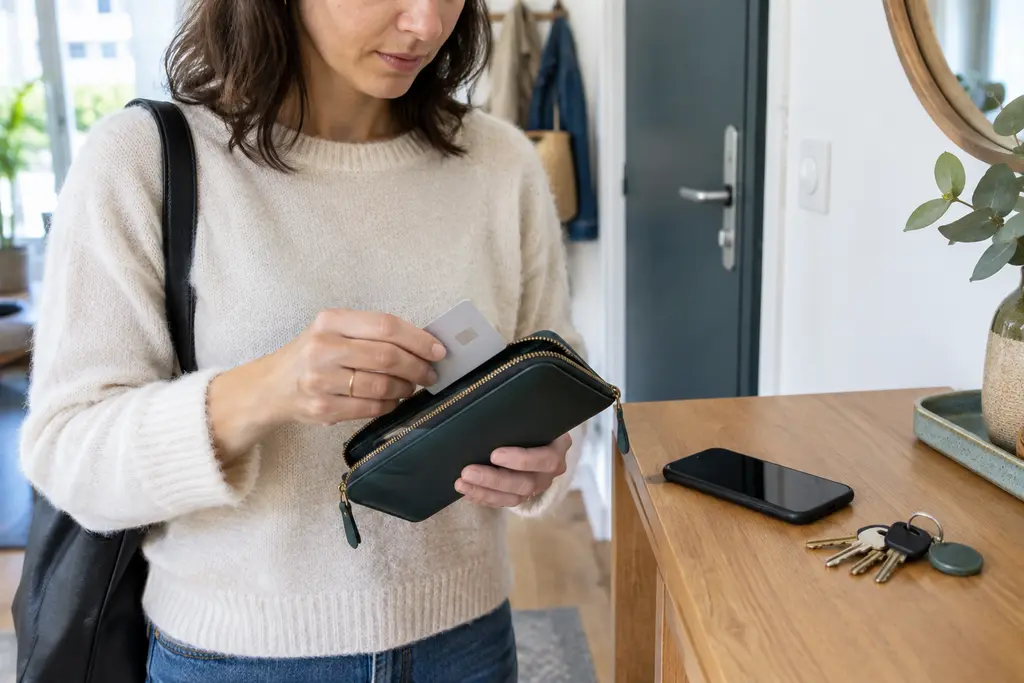 Une femme retire une carte neutre de son portefeuille près de son téléphone retourné.